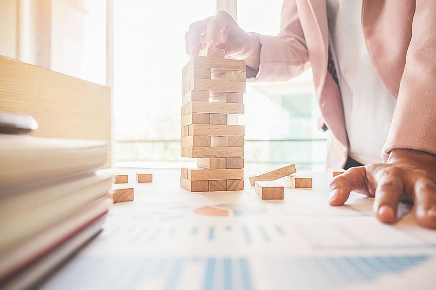 Hand of business man planning, risk and strategy in business.Businessman gambling placing wooden block on a tower.